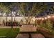 Enchanting backyard with dining area under string lights, fire pit, and lush greenery, creating an inviting outdoor retreat at 1513 W Mitchell Dr, Phoenix, AZ 85015