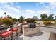This outdoor kitchen has a built-in BBQ, chairs with red cushions, and desert landscaping at 18514 N Laguna Azul Ct, Surprise, AZ 85374