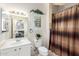 Well-lit bathroom with a single sink vanity, toilet, window with blind, and shower with a decorative curtain at 18867 N Cactus Flower Way, Surprise, AZ 85387