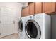Well-lit laundry room featuring a modern washer and dryer set with cabinets above at 18867 N Cactus Flower Way, Surprise, AZ 85387