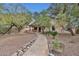 Lush backyard featuring desert landscaping, mature trees, rock pathway, and a covered patio at 20838 N 39Th Dr, Glendale, AZ 85308