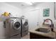 This laundry room has stainless steel washer and dryer units, a sink with granite countertop, and an adjacent shelf at 20838 N 39Th Dr, Glendale, AZ 85308