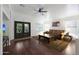 Bright living room with hardwood floors, large windows, ceiling fan, and a decorative wood and wrought iron double door at 20838 N 39Th Dr, Glendale, AZ 85308