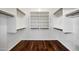 Spacious walk-in closet with wood floors, white shelves, and hanging rods at 20838 N 39Th Dr, Glendale, AZ 85308