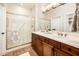 Bathroom featuring double sinks, wood cabinets, a glass shower, and tile floors at 22236 N Arrellaga Dr, Sun City West, AZ 85375