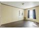 A spacious room with dark floors, neutral walls, and a bright window with blue curtains at 255 S 92Nd Pl, Mesa, AZ 85208