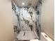 Updated bathroom shower with stylish marble-like tile surround and modern fixtures at 3338 W Palmaire Ave, Phoenix, AZ 85051