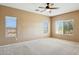 Bright bedroom with tan walls, three windows, and a ceiling fan at 44390 W Buckhorn Trl, Maricopa, AZ 85138