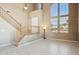 Bright living room with soaring ceilings, large windows, staircase and tile flooring at 44390 W Buckhorn Trl, Maricopa, AZ 85138