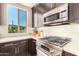 Bright kitchen showcases stainless appliances, granite counters, dark cabinetry, and a view from the window at 4803 N Woodmere Fairway -- # 2012, Scottsdale, AZ 85251