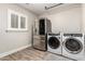 A contemporary laundry room boasts stainless steel appliances and a window, combining utility with style at 5333 E Catalina Ave, Mesa, AZ 85206