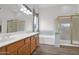 Well-lit bathroom features a double vanity, soaking tub, and glass-enclosed shower at 6793 W Angela Dr, Glendale, AZ 85308