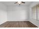 Bright, empty bedroom with wood-look floors, neutral walls, a ceiling fan, and natural light streaming in from the window at 6793 W Angela Dr, Glendale, AZ 85308