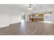 Open floor plan living room with wood floors, white walls, and connected kitchen and hallway at 6793 W Angela Dr, Glendale, AZ 85308