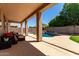 Covered patio with comfortable seating overlooking the swimming pool with rock waterfall feature at 9511 E Kiva Ave, Mesa, AZ 85209