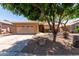 Charming single-story home featuring a two-car garage and xeriscaped front yard shaded by mature trees at 9511 E Kiva Ave, Mesa, AZ 85209