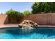Inviting pool features a rock waterfall feature, complemented by lush landscaping and privacy fence at 9511 E Kiva Ave, Mesa, AZ 85209