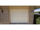 Attached garage with a contemporary white panel door and brick facade, offering secure parking at 11012 W Caron Dr, Sun City, AZ 85351