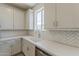 The kitchen has white cabinets, backsplash, countertops, and a stainless steel dishwasher at 11300 N Casa Dega N Dr # 1047, Surprise, AZ 85388