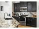 Close up of modern kitchen with granite countertops, stainless steel appliances, and black cabinetry at 11959 W Vernon Ave, Avondale, AZ 85392