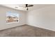 Bright bedroom features neutral carpet, a ceiling fan, and a window with a view of a home at 14823 S 13Th Pl, Phoenix, AZ 85048