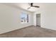 This bright bedroom includes neutral carpet, a ceiling fan, closet, and a window overlooking the neighborhood at 14823 S 13Th Pl, Phoenix, AZ 85048