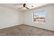 This bright bedroom includes a ceiling fan and a window with a view of the neighbor's home at 14823 S 13Th Pl, Phoenix, AZ 85048