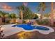 Tranquil backyard pool with rock waterfall, lush landscaping, and ambient lighting for evening enjoyment at 14823 S 13Th Pl, Phoenix, AZ 85048