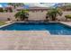 Backyard pool with travertine deck, water feature, lush landscaping, and privacy wall at 19571 E Strawberry Dr, Queen Creek, AZ 85142