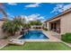 Backyard pool with travertine deck, water feature, lush landscaping, cornhole boards, and green grass at 19571 E Strawberry Dr, Queen Creek, AZ 85142