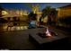 Inviting pool area features a fire pit, ambient lighting, and mature palm trees for a relaxing ambiance at 19571 E Strawberry Dr, Queen Creek, AZ 85142