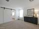 Bright primary bedroom with a barn door, and carpet at 20563 W White Rock Rd, Buckeye, AZ 85396