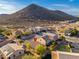 An aerial view of the home nestled in a desert community with a mountain backdrop under a clear, sunny sky at 23005 N 19Th Way, Phoenix, AZ 85024