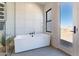 Modern white bathtub next to an exterior door that offers a view of the surrounding desert landscape at 23656 N 123Rd St # 240, Scottsdale, AZ 85255