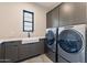 Modern laundry room with gray cabinets, stone countertops, and stainless steel washer and dryer at 23656 N 123Rd St # 240, Scottsdale, AZ 85255