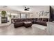 Spacious living room features a cozy fireplace, ceiling fan, and a large leather sectional at 26066 N 72Nd Ave, Peoria, AZ 85383