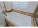 Close-up of a neutral toned soaking tub with tile surround and window at 32835 N 70Th St, Scottsdale, AZ 85266