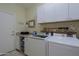 Well-equipped laundry room featuring front-load washer and dryer, with overhead white cabinets at 32835 N 70Th St, Scottsdale, AZ 85266