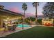 Stunning backyard at dusk featuring a pool, covered patio, lush greenery, and enchanting string lights at 3473 E Wyatt Way, Gilbert, AZ 85297