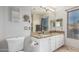 Bright bathroom featuring double sinks with granite countertops and white cabinets, complete with elegant mirror and a toilet at 3473 E Wyatt Way, Gilbert, AZ 85297