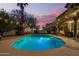 Beautiful pool area illuminated at twilight, surrounded by lush landscaping, and a covered patio at 3473 E Wyatt Way, Gilbert, AZ 85297