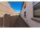 A narrow, gravel-filled side yard showcases the home's exterior with stucco siding and framed windows against a vibrant blue sky at 3943 E Ficus Way, Gilbert, AZ 85298