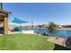 A waterfront backyard with artificial turf, seating, string lights, and a calming water view at 40835 W Agave Rd, Maricopa, AZ 85138