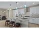 Kitchen island with granite countertop, sink, pendant lights, white cabinets and seating at 40835 W Agave Rd, Maricopa, AZ 85138