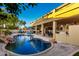 Inviting backyard with pool and rock waterfall, covered patio with outdoor kitchen, and lounge area at 4812 S Windstream Pl, Chandler, AZ 85249