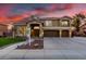 Beautiful two-story home with a well-manicured lawn, three-car garage and mature palm trees at sunset at 4812 S Windstream Pl, Chandler, AZ 85249