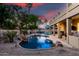 Beautiful backyard pool with rock waterfall, covered patio, and desert landscaping under colorful sky at 4812 S Windstream Pl, Chandler, AZ 85249
