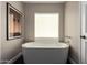 Bright bathroom features a free-standing soaking tub beneath a window, next to a closed door at 8424 E San Bernardo Dr, Scottsdale, AZ 85258