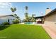 Lush backyard featuring a sparkling pool, well-maintained lawn, palm trees, and a covered patio area at 8621 E Vista Dr, Scottsdale, AZ 85250