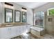Bright bathroom features a double vanity, decorative mirrors, soaking tub, and glass enclosed shower at 903 W Raven Dr, Chandler, AZ 85286
